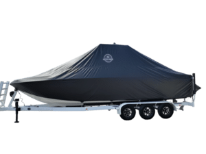 A boat covered with a dark protective cover is secured on a white trailer with multiple wheels against a plain background.