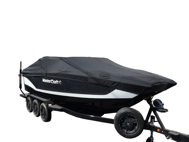 A black and white MasterCraft boat on a trailer, covered with a fitted black tarp.