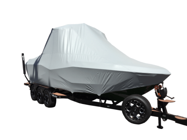 A boat covered with a gray protective tarp is secured on a black trailer with multiple wheels.