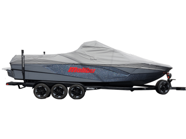 A speedboat covered with a gray tarp is secured on a triple-axle trailer.