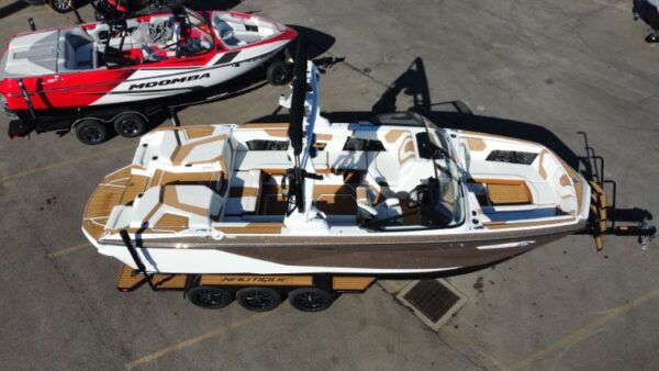 An overhead view of a boat on a trailer with a distinctive brown and white design. Another boat with red and white colors is seen nearby.