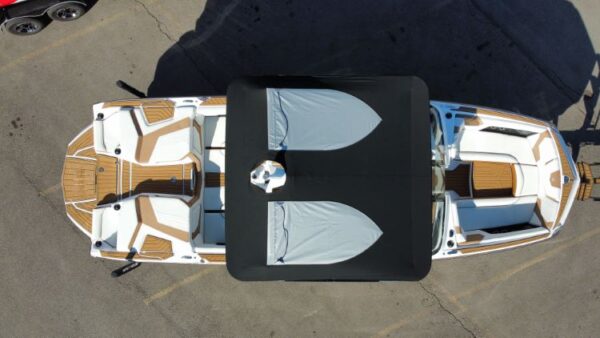 Aerial view of a boat with a large black and gray canopy, featuring white and tan seating areas at the front and rear. The boat is parked on a paved surface.