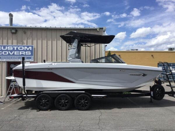 A white and red speedboat on a trailer is parked outside a building.