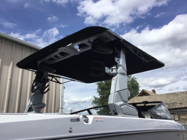 A boat with a black canopy is parked near a building, under a partly cloudy sky.