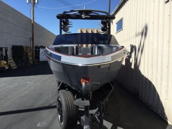 A boat on a trailer is parked in an alleyway between two buildings, positioned with the front facing towards the camera.